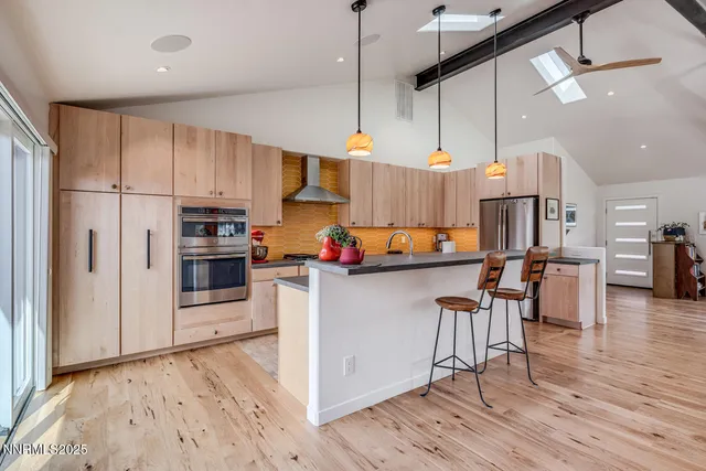 a kitchen view with stainless steel appliances kitchen island granite countertop a refrigerator a stove and white cabinets with wooden floor