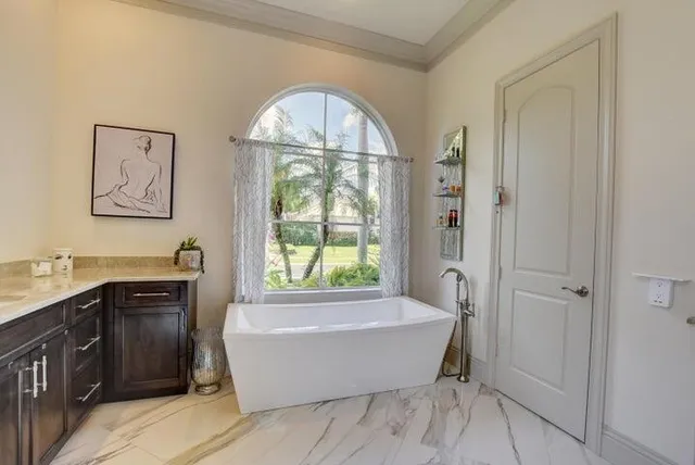 a spacious bathroom with a tub a double vanity sink a window and a mirror