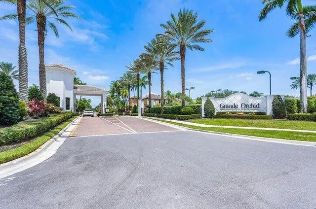 a view of a house with a yard and palm trees