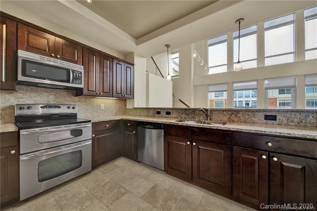 4300 Sharon Road, Unit 407 Charlotte, NC 28211 - Photo 6 of 10 a kitchen with stainless steel appliances granite countertop wooden cabinets a stove a sink and a microwave
