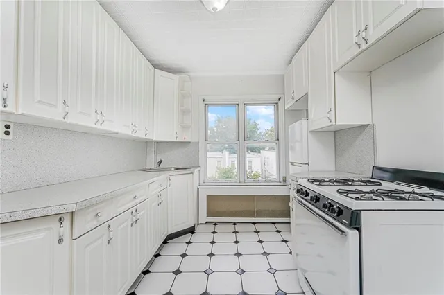 a kitchen with white cabinets and sink