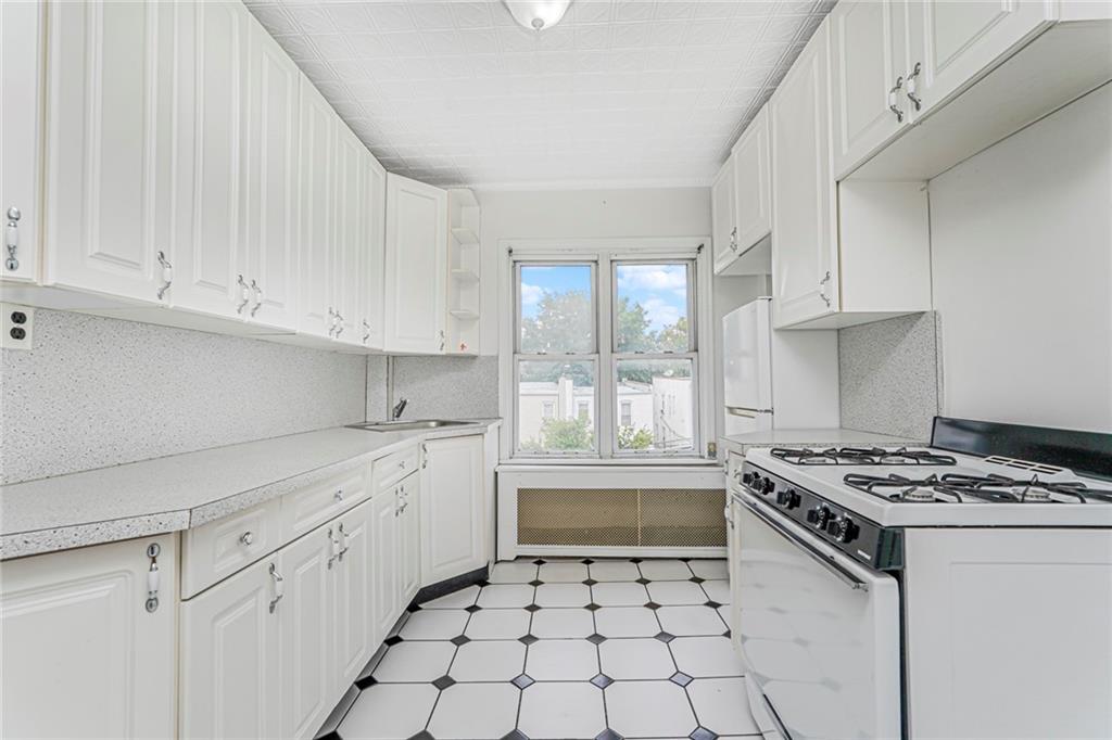 329 80th Street Brooklyn, NY 11209 - Photo 14 of 34 a kitchen with white cabinets and appliances