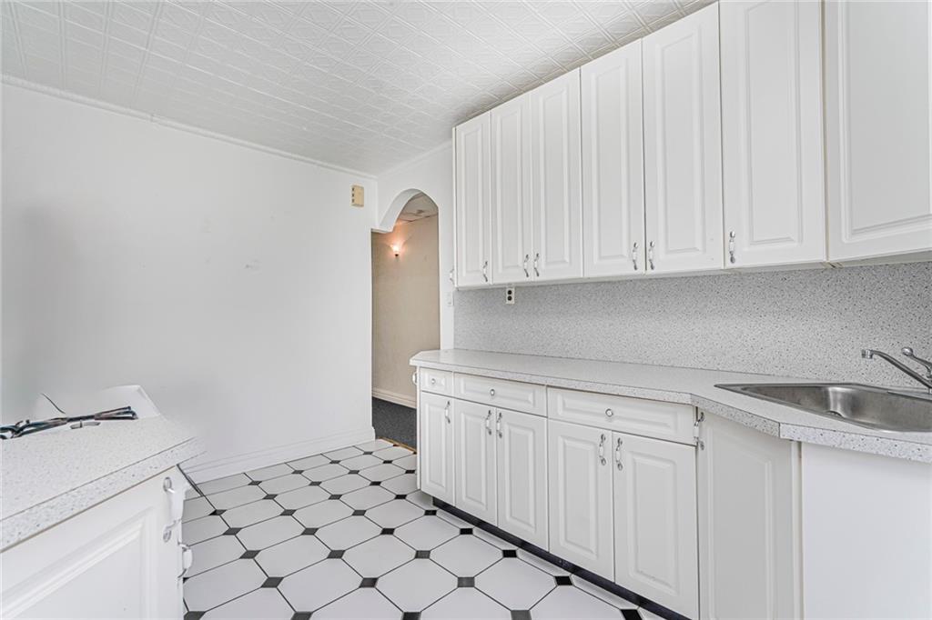 329 80th Street Brooklyn, NY 11209 - Photo 15 of 34 a kitchen with white cabinets and sink