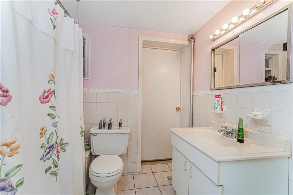 329 80th Street Brooklyn, NY 11209 - Photo 5 of 34 a bathroom with a sink a toilet and shower curtain