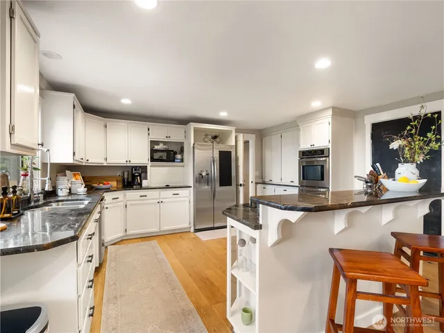 a large white kitchen with stainless steel appliances granite countertop a stove and a sink