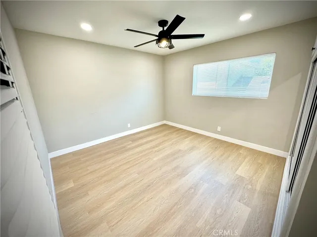 an empty room with wooden floor and a ceiling fan