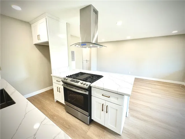 a kitchen with a stove and a wooden floor