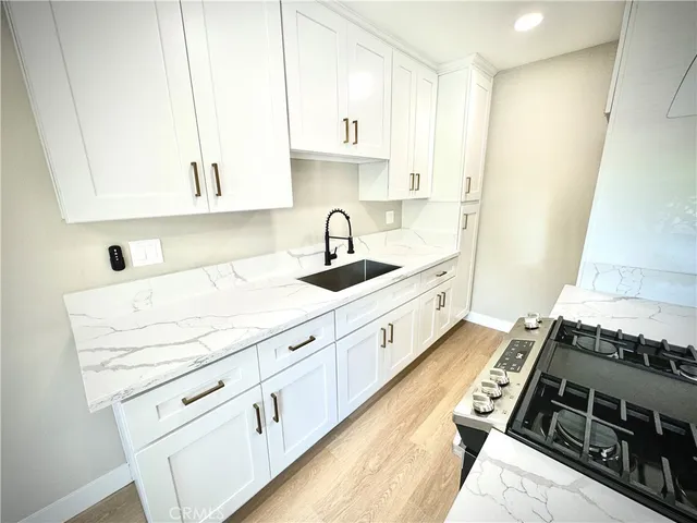 a kitchen with granite countertop a sink a stove and cabinets