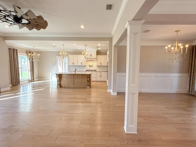 a large kitchen with kitchen island a stove a sink dishwasher and white cabinets with wooden floor