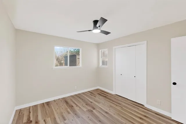 a view of empty room with wooden floor and fan