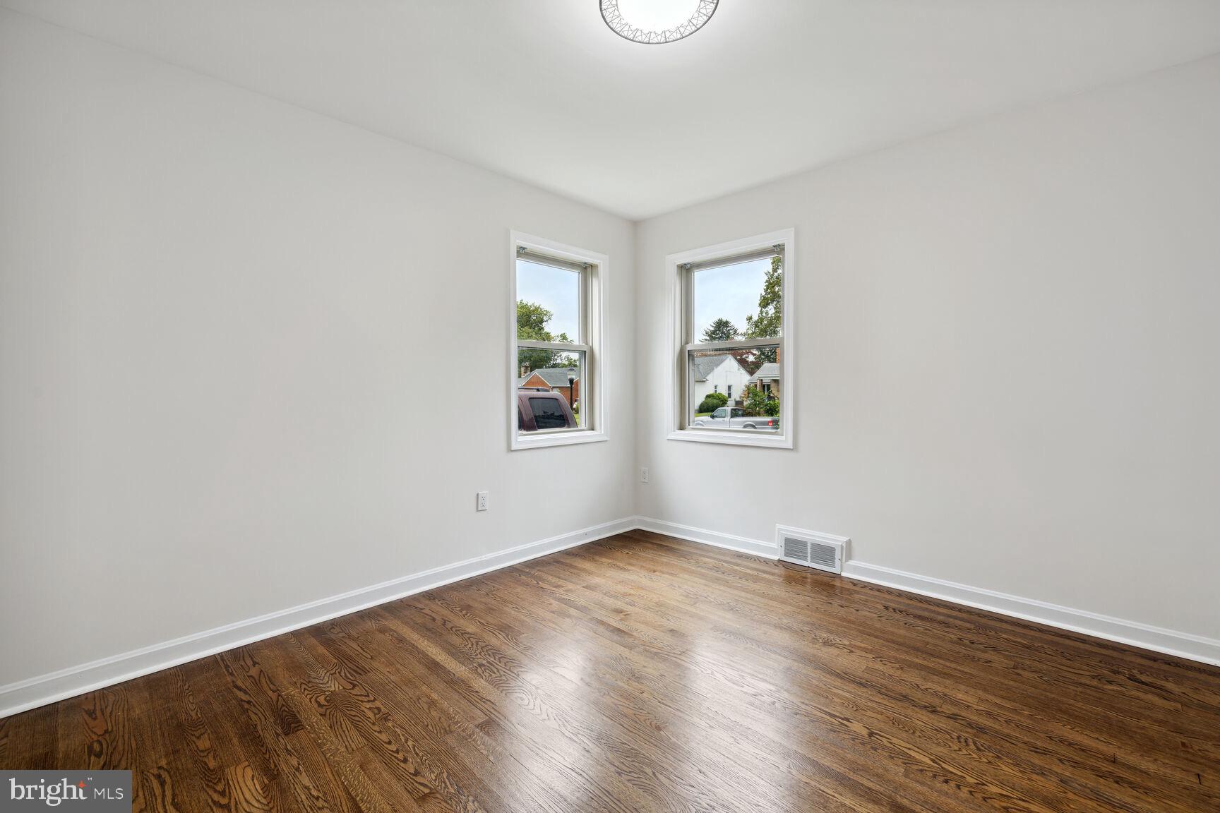 606 Biggs Avenue Frederick, MD 21702 - Photo 8 of 20 an empty room with wooden floor and windows