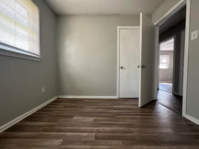 a view of an empty room with wooden floor and a window