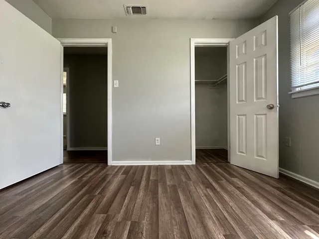 an empty room with wooden floor and closet