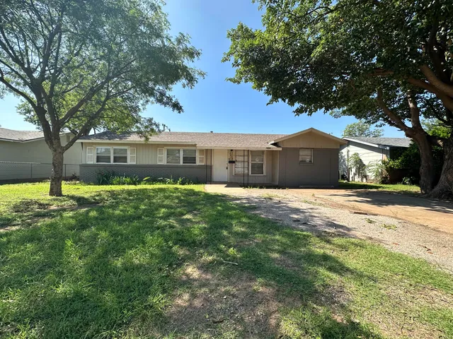 a front view of a house with a yard and trees