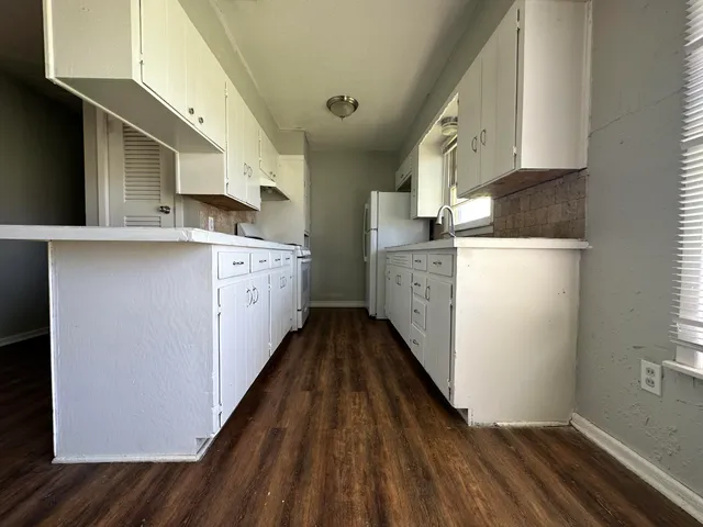 a kitchen with a sink a stove top oven and wooden floor