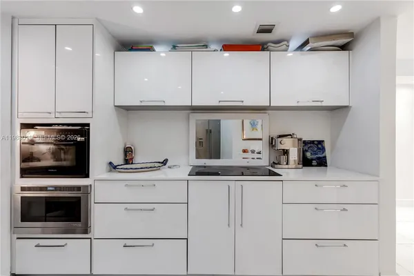 a kitchen with granite countertop white cabinets and stainless steel appliances