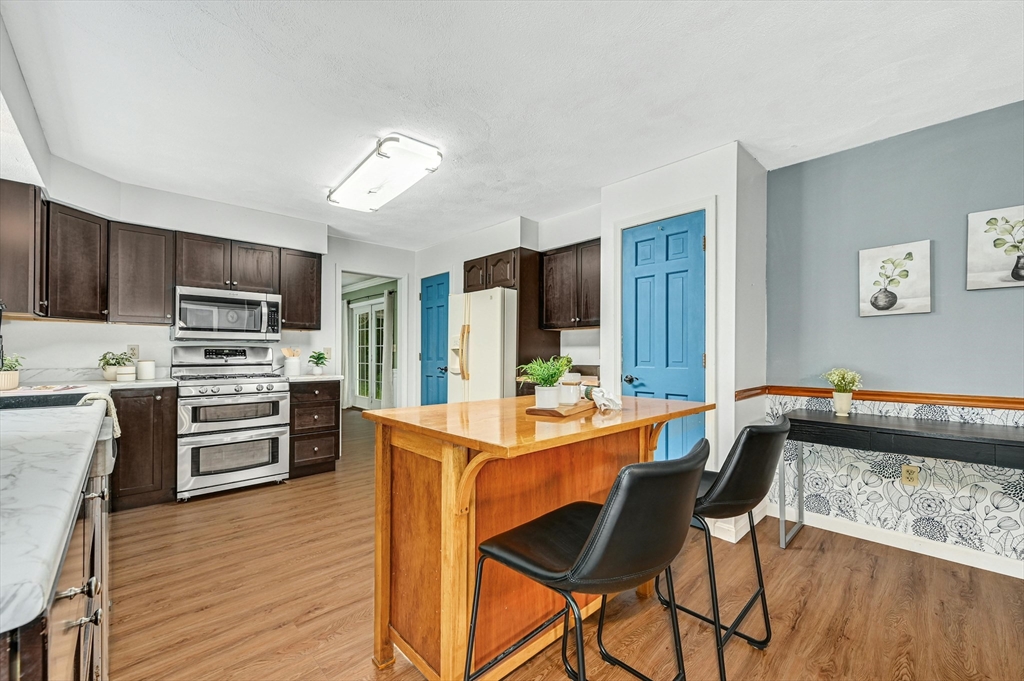 210 New Boston Road Sturbridge, MA 01566 - Photo 12 of 42 a kitchen with stainless steel appliances granite countertop a stove top oven a sink dishwasher a dining table and chairs with wooden floor