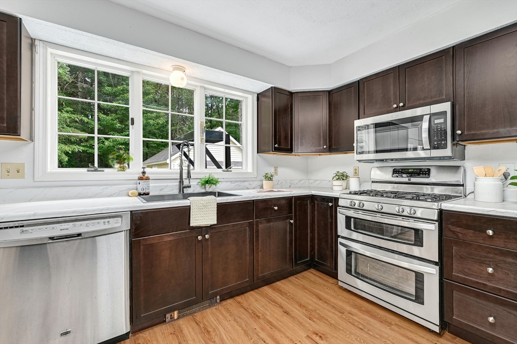 210 New Boston Road Sturbridge, MA 01566 - Photo 13 of 42 a kitchen with granite countertop a stove a sink and dishwasher wooden cabinets with wooden floor