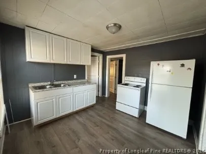 a kitchen with sink a refrigerator and white cabinets