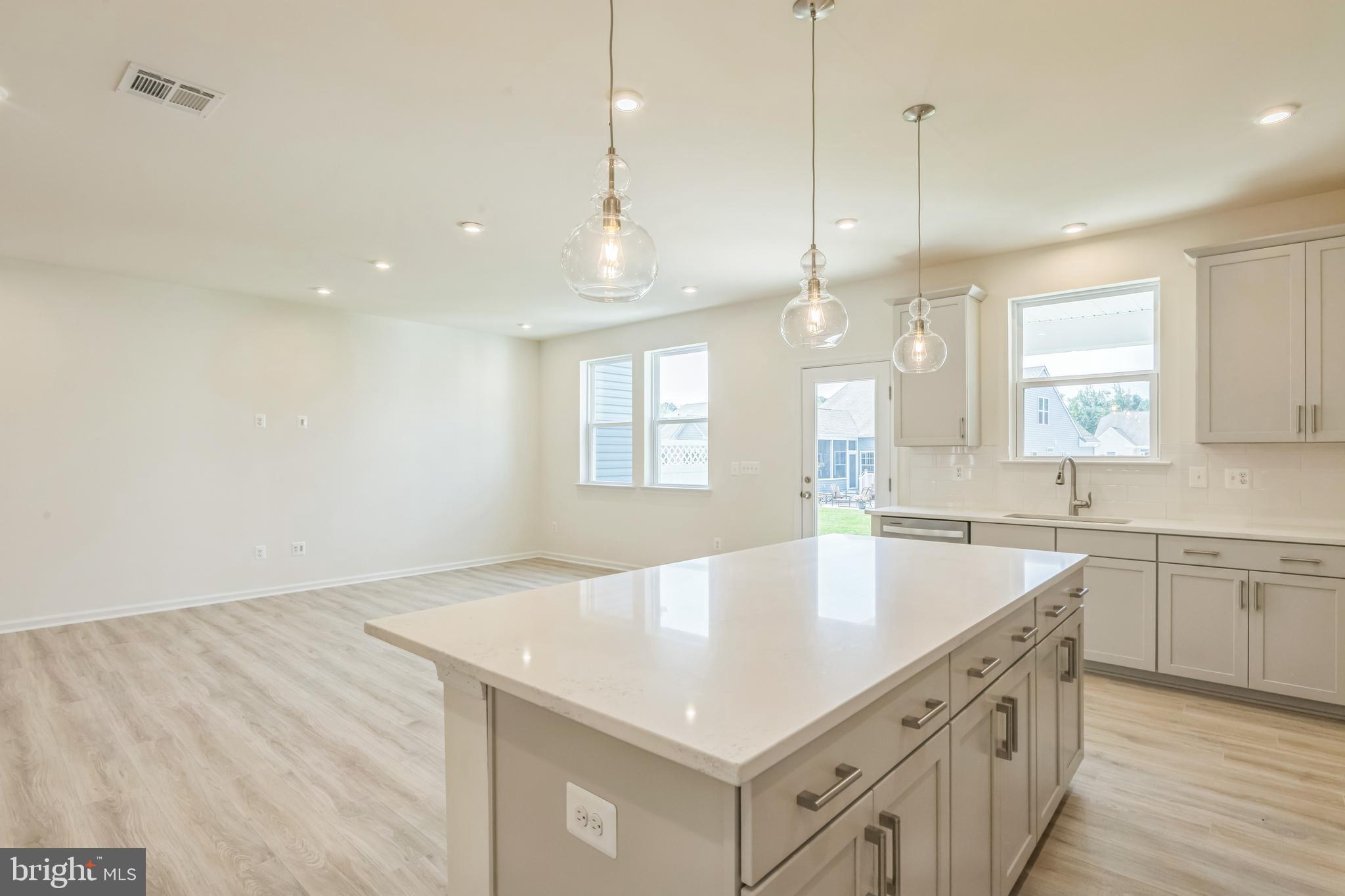 392 Scranton Lane Ocean View, DE 19970 - Photo 6 of 15 a large white kitchen with a sink a center island a stove and a wooden floor