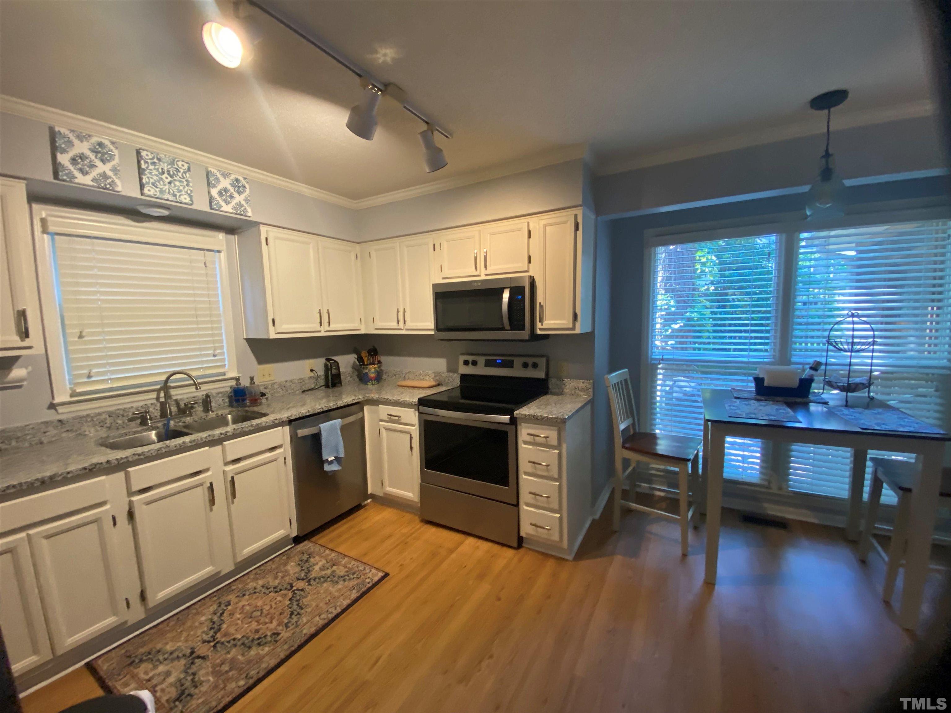4728 Worchester Place Raleigh, NC 27604 - Photo 5 of 7 a kitchen with granite countertop a stove top oven a sink dishwasher a dining table and chairs with wooden floor