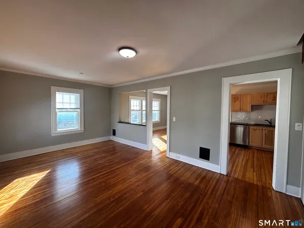 a view of empty room with wooden floor and fan