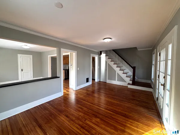 a view of an empty room with wooden floor and a window