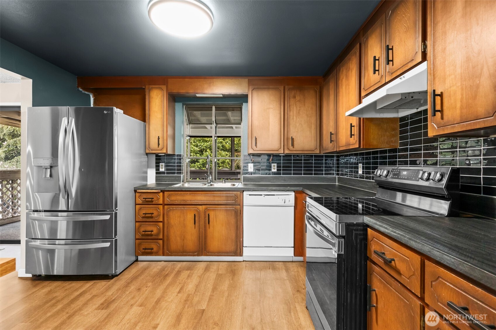 10329 99th Street Southwest Tacoma, WA 98498 - Photo 6 of 25 a kitchen with stainless steel appliances granite countertop a refrigerator a sink a stove a microwave and wooden floors