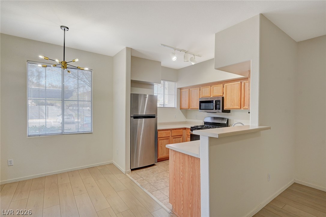 9050 West Warm Springs Road, Unit 1147 Las Vegas, NV 89148 - Photo 8 of 36 A compact kitchen with blonde wood cabinetry and stainless steel appliances seamlessly transitions to a sun-filled dining area.