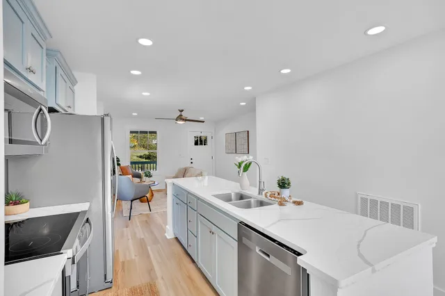 a kitchen with a sink dishwasher and a stove with wooden floor