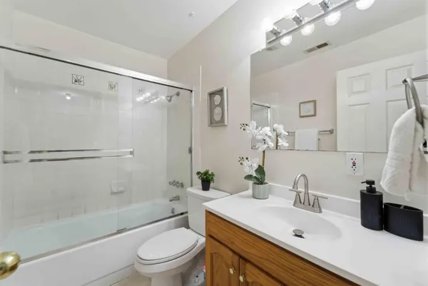a bathroom with a sink a toilet a mirror and shower