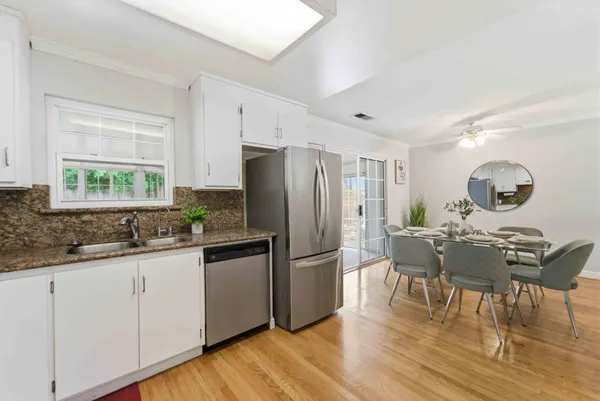 a kitchen with granite countertop a refrigerator a stove a dining table and chairs