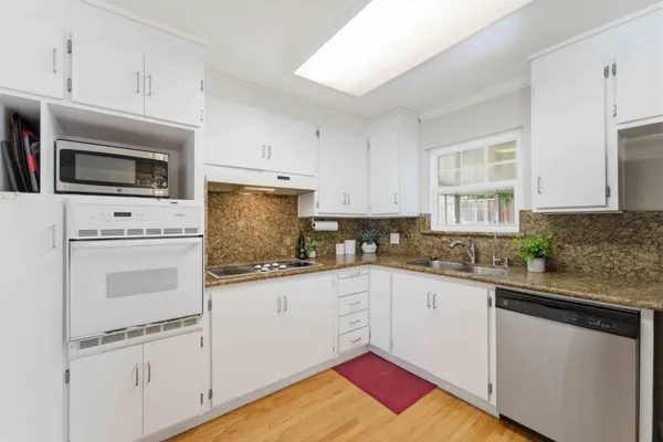 a kitchen with granite countertop white cabinets and white appliances