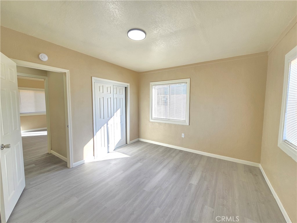 8651 S Loop California City, CA 93505 - Photo 11 of 16 an empty room with wooden floor and windows