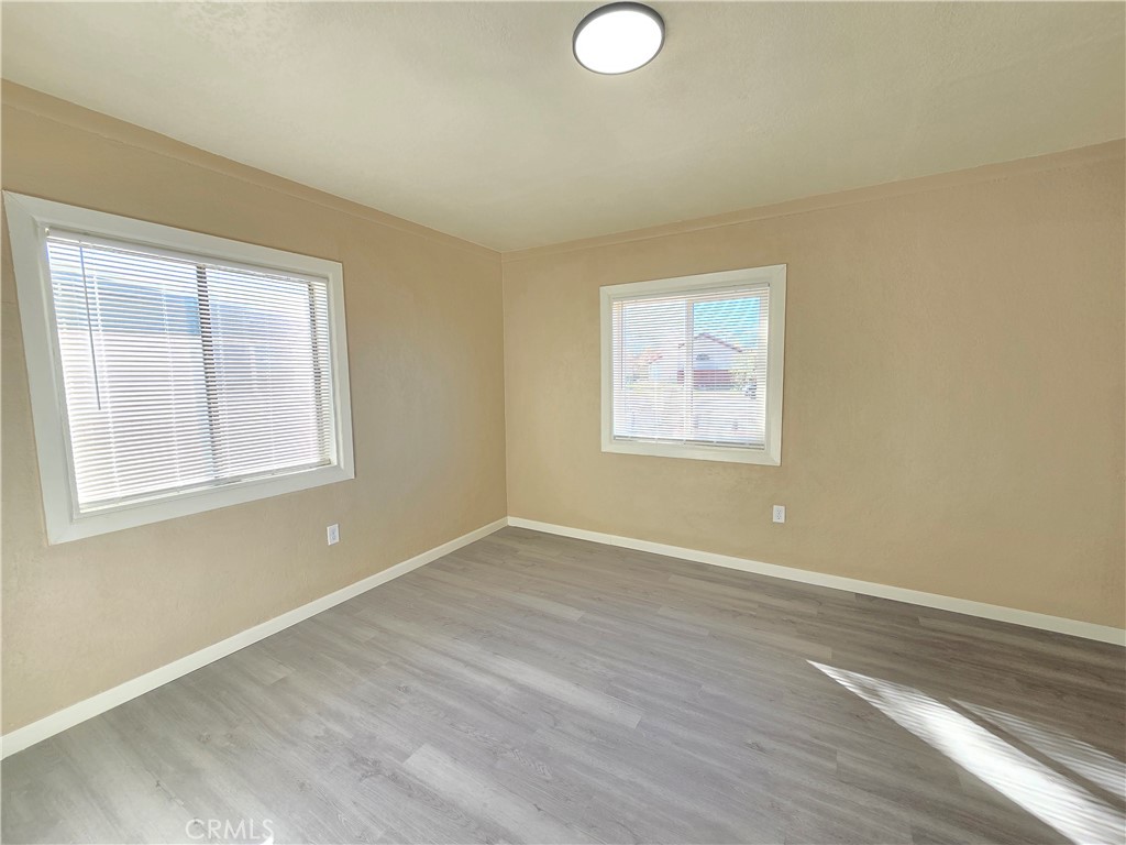 8651 S Loop California City, CA 93505 - Photo 12 of 16 an empty room with wooden floor and windows