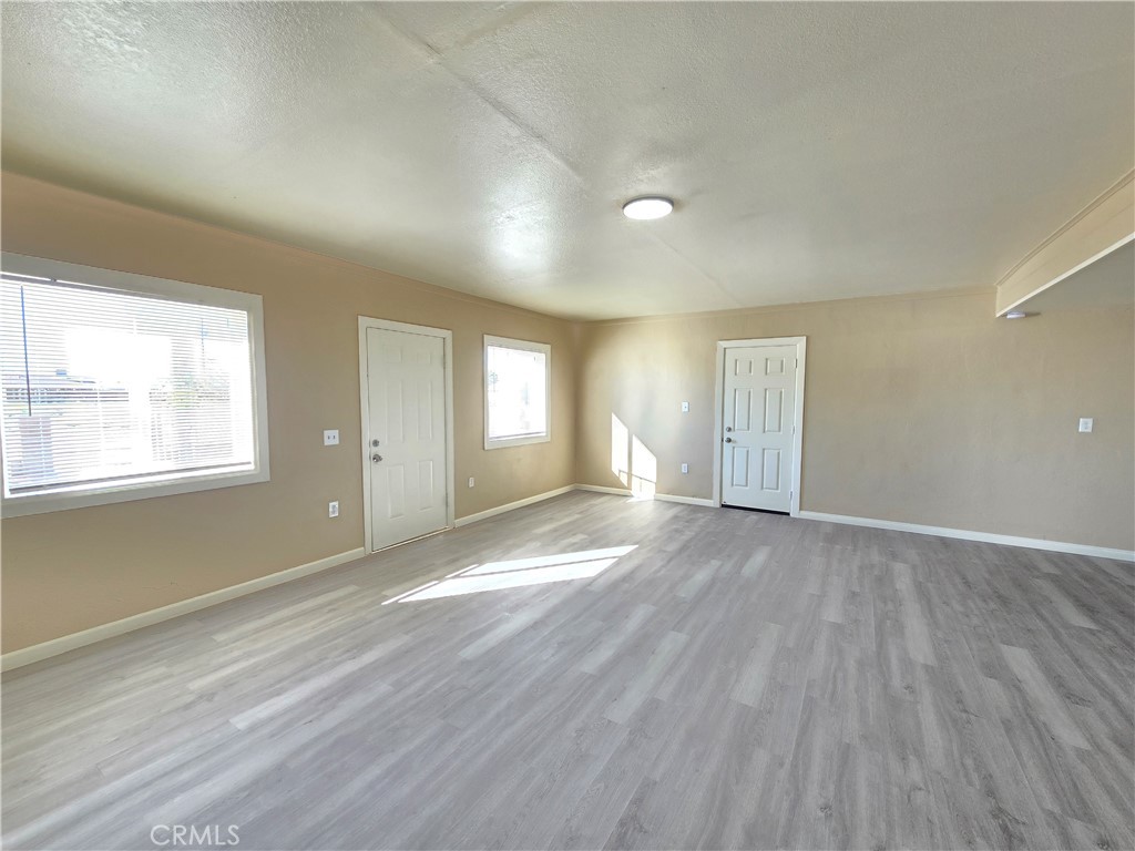 8651 S Loop California City, CA 93505 - Photo 7 of 16 an empty room with wooden floor and windows