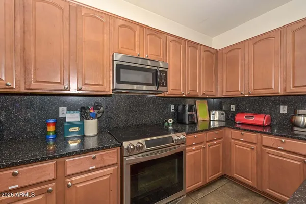 a kitchen with granite countertop a stove top oven microwave and cabinets