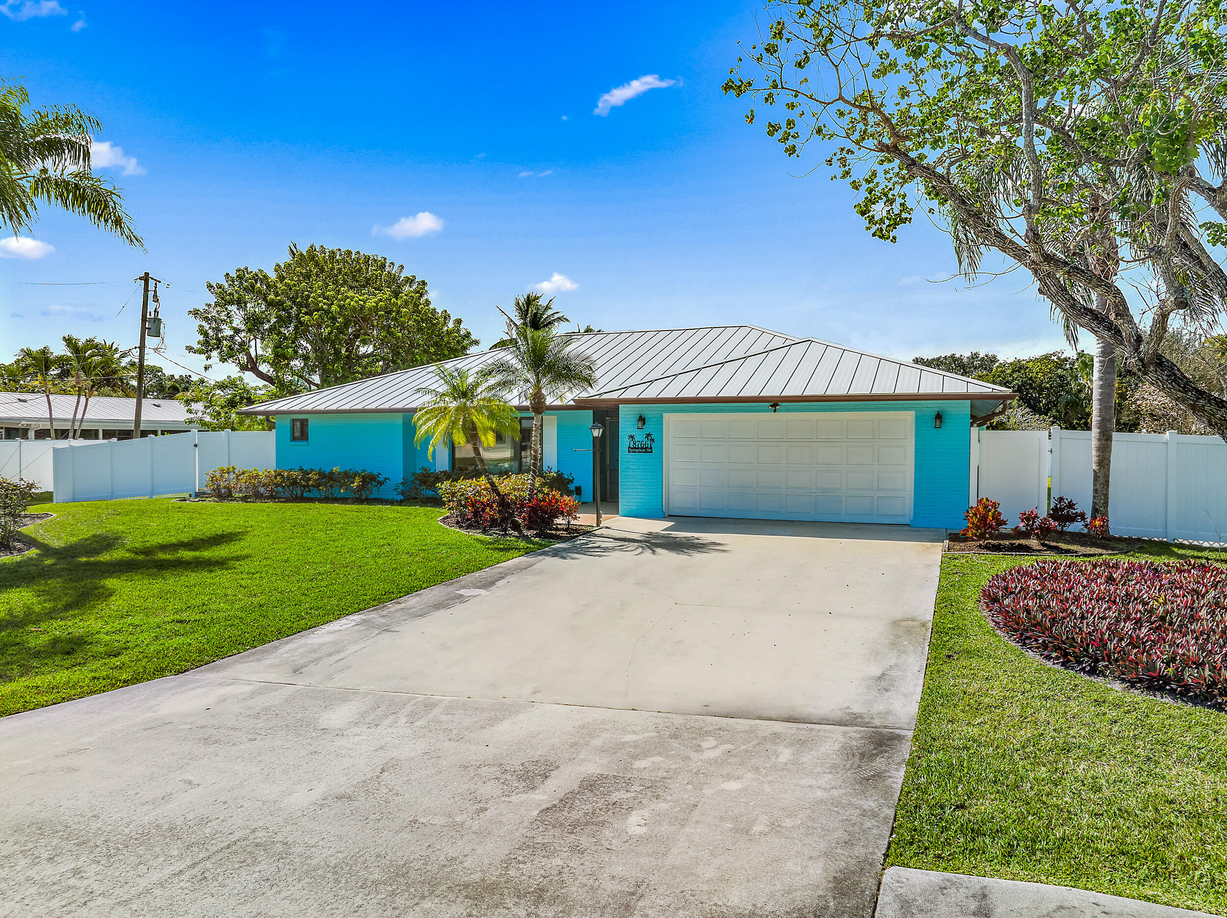 8766 Southeast Longview Drive Hobe Sound, FL 33455 - Photo 3 of 27 a front view of a house with a garden and yard