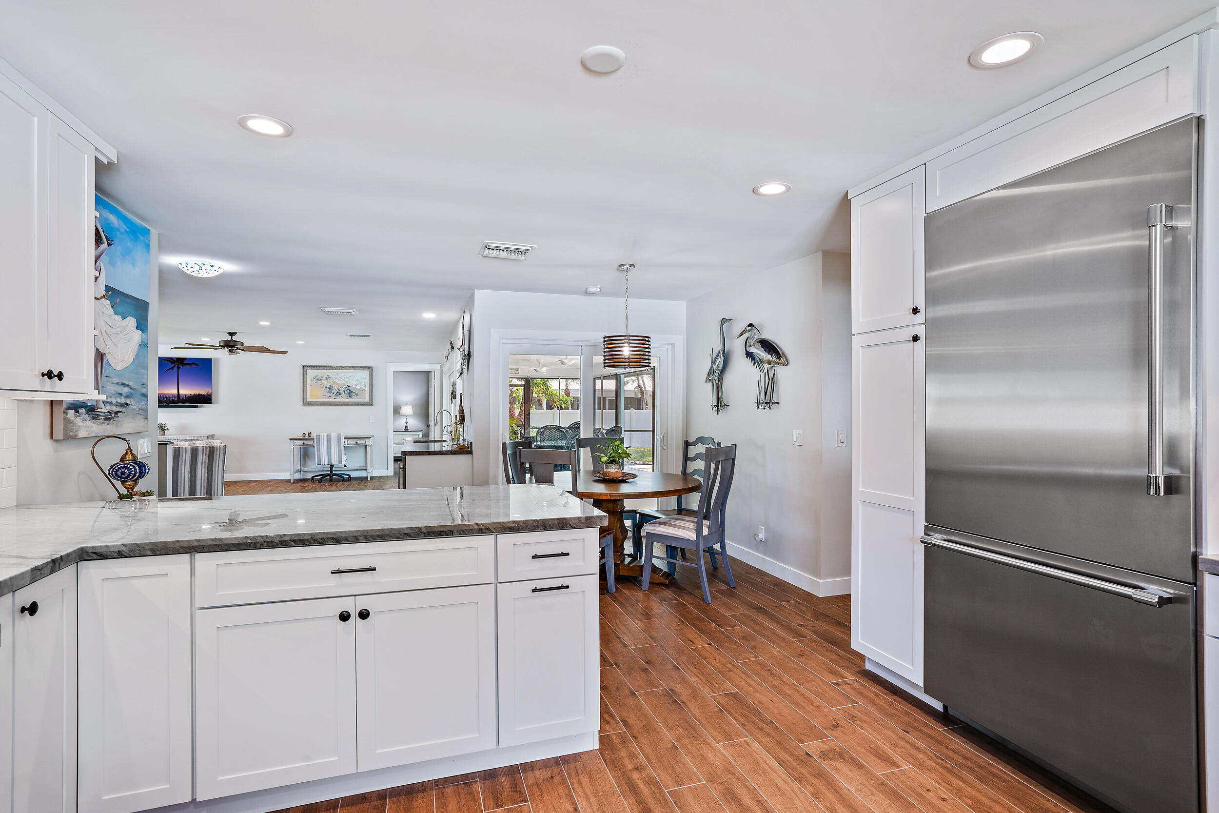 8766 Southeast Longview Drive Hobe Sound, FL 33455 - Photo 7 of 27 a kitchen with kitchen island granite countertop a sink cabinets and stainless steel appliances