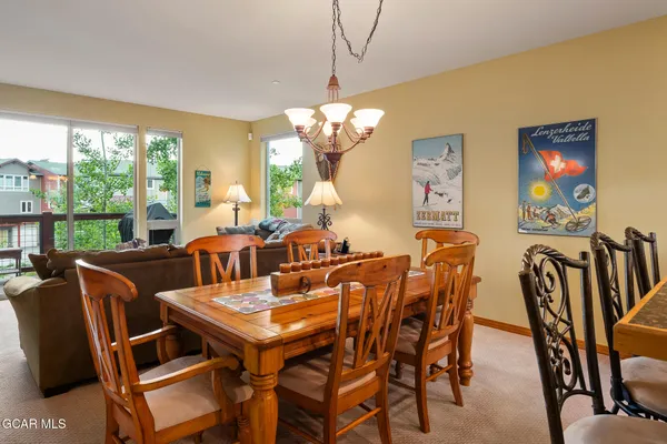 a view of a dining room with furniture a chandelier and large windows