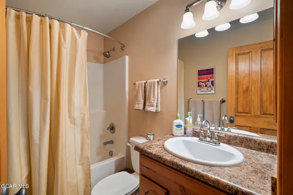 a bathroom with a granite countertop sink a toilet and a mirror