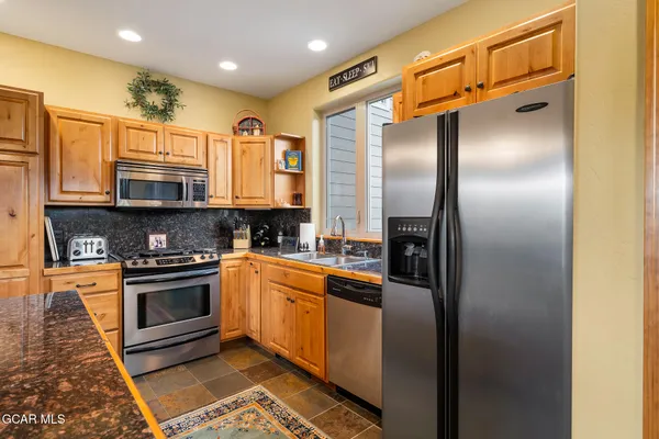 a kitchen with stainless steel appliances granite countertop a refrigerator a stove and a sink with wooden floor