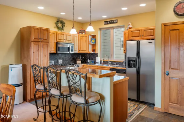 a kitchen with stainless steel appliances granite countertop a refrigerator a oven a sink and a dining table