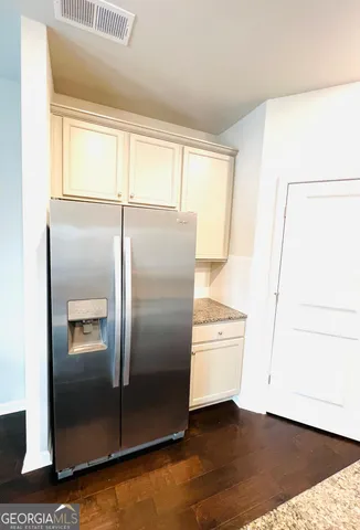a kitchen with metallic refrigerator and wooden floor