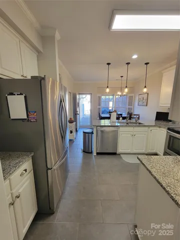 a kitchen with stainless steel appliances granite countertop a table chairs and a refrigerator