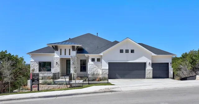 a front view of a house with garage and plants