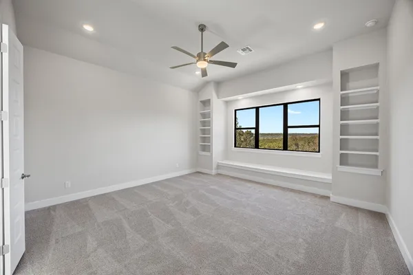 an empty room with windows and fan