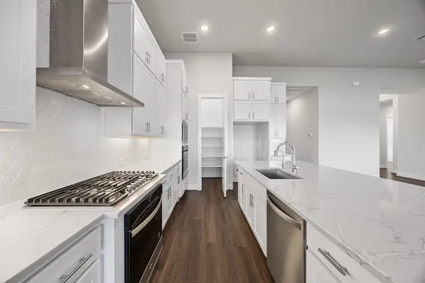 a kitchen with stainless steel appliances a sink a stove top oven a counter space and cabinets