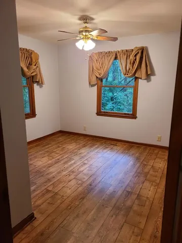 an empty room with wooden floor closet and a ceiling fan