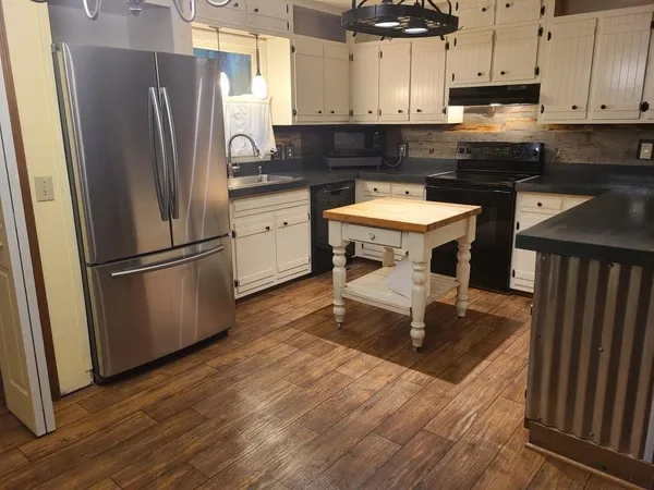 a kitchen with kitchen island a sink dishwasher a refrigerator and a stove with wooden floor